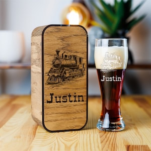 May include: A wooden box and a beer glass with a train theme. The box has a laser-etched image of a train and the name "Justin". The glass is filled with dark beer and has the name "Justin" etched on it.