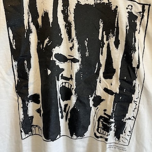 May include: Black and white graphic print of three screaming faces on a white t-shirt. The text "Radio Cauldron Eclipse" and "1991 Clive Barker" is printed on the bottom of the shirt.