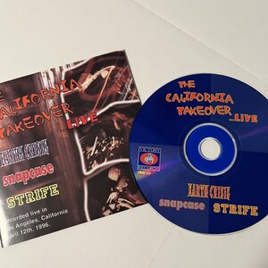 May include: A blue CD with the text "The California Takeover...Live" and "snapcase STRIFE" on it. The CD is in a plastic case with a picture of a band on the front. The text "EARTH CRISIS" is also visible on the case.