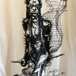 May include: Black and white line drawing of a person with a mohawk hairstyle. The person is wearing a studded leather jacket and pants. The drawing is signed "Cenobite" and "Clive Barker 1986".