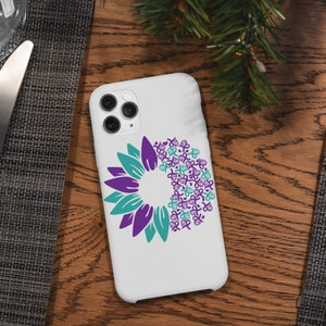 May include: White iPhone case with a purple and teal sunflower design. The sunflower is made up of multiple purple and teal ribbon shapes.