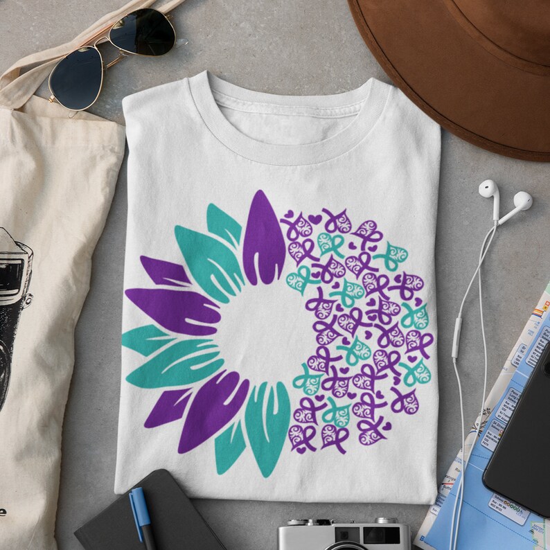 May include: White t-shirt with a purple and teal sunflower design. The sunflower is made up of multiple small hearts and ribbons.