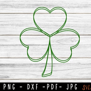 May include: A green shamrock outline on a white wood background.