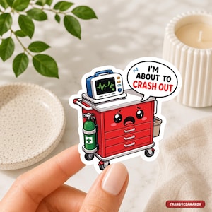 May include: A die-cut sticker featuring a red medical crash cart with a cartoon face showing a distressed expression. The cart has a green oxygen tank, a heart monitor on top, and a speech bubble with the text I'M ABOUT TO CRASH OUT.