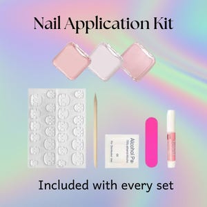 May include: A nail application kit with three pink and white containers, nail adhesive, a pink nail file, a cuticle stick, and alcohol wipes. The text "Nail Application Kit" and "Included with every set" are displayed.