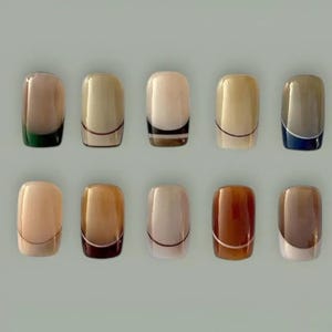 May include: A set of ten artificial nails, each with a different design. The nails feature a variety of colors, including beige, brown, and white, with accents of green, black, and blue. Each nail has a curved, rectangular shape.