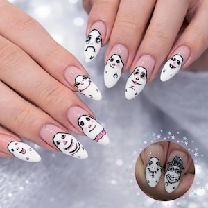 May include: White nail art featuring cartoon faces with various expressions. Each nail showcases a different character, with details in black and pink. The nails are almond-shaped and have a clear base with a pinkish hue.