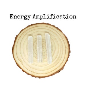 May include: Three white selenite wands on a wooden slice. The text "Energy Amplification" is above the wands.