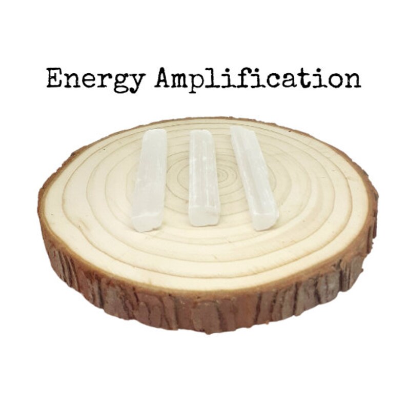 May include: Three white selenite sticks on a wooden slice. The sticks are arranged in a row and are about 3 inches long. The text "Energy Amplification" is written above the sticks.
