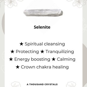 May include: A white selenite crystal, a type of mineral known for its calming and cleansing properties. The text on the card reads "Selenite", "Spiritual cleansing", "Protecting", "Tranquilizing", "Energy boosting", "Calming", "Crown chakra healing", and "A Thousand Crystals".
