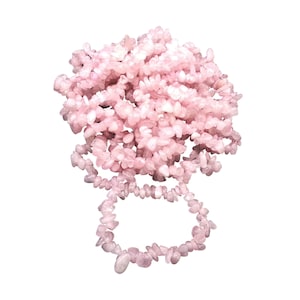 May include: A large pile of pink rose quartz chips, with a smaller pile of chips forming a circle.