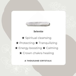 May include: A white selenite crystal, a type of mineral known for its calming and cleansing properties. The text on the image reads "Selenite", "Spiritual cleansing", "Protecting", "Tranquilizing", "Energy boosting", "Calming", "Crown chakra healing", and "A Thousand Crystals".