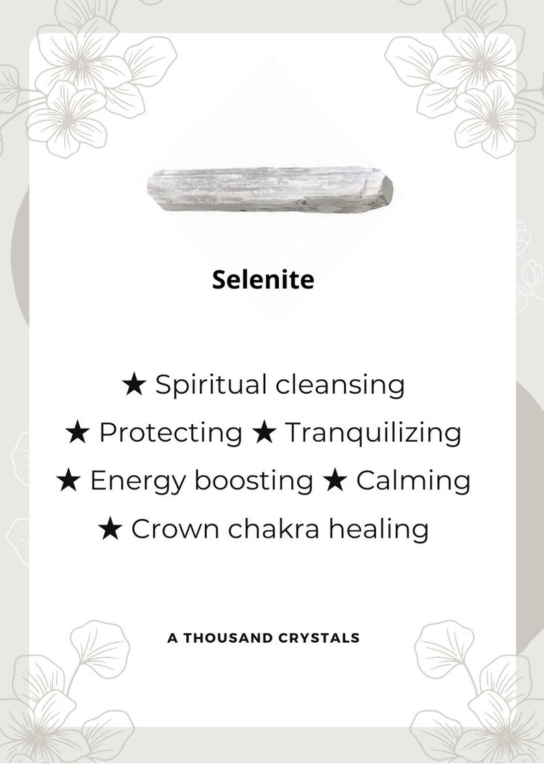 May include: A white selenite crystal, a type of mineral known for its calming and cleansing properties. The text on the card reads "Selenite", "Spiritual cleansing", "Protecting", "Tranquilizing", "Energy boosting", "Calming", "Crown chakra healing", and "A Thousand Crystals".