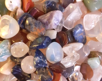 Può includere: Una collezione di pietre levigate in vari colori, tra cui blu, verde, rosso, viola e bianco. Le pietre sono lisce e lucidate e sono disposte in uno schema casuale.