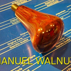 Pode incluir: Um close-up de uma maçaneta de madeira com acabamento em mármore vermelho e marrom. A maçaneta está sobre uma superfície azul com linhas amarelas e o texto "MANUEL WALNUT".