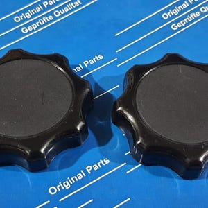 May include: Two black plastic knobs with a starburst design. The knobs have a smooth, black surface and are designed for use with a variety of appliances.