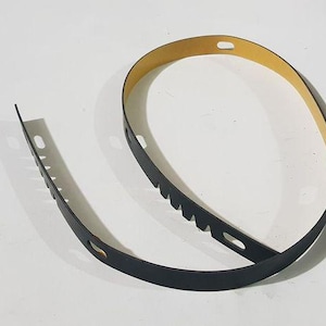 May include: Black rubber trim with a brown backing. The trim has a series of small holes along the edge.