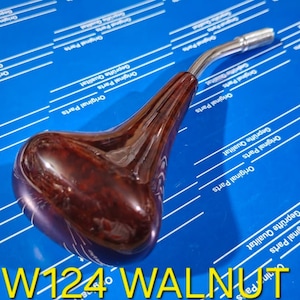 May include: A brown wooden gear shift knob with a chrome extension. The knob has a wood grain pattern and the text "W124 WALNUT" is printed on the bottom.
