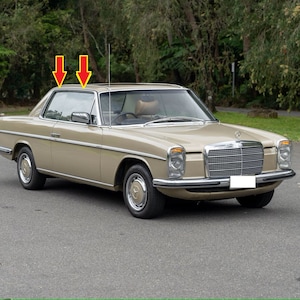 Puede incluir: Un coupé Mercedes-Benz beige de la década de 1970 con detalles cromados. El coche tiene una parrilla negra y parachoques negros. El coche está aparcado en una superficie pavimentada.