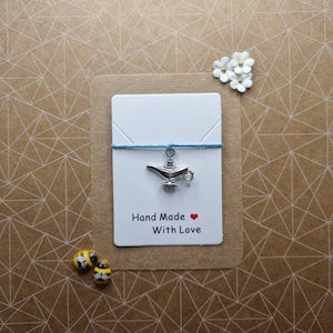 May include: A silver genie lamp charm on a blue string with a white card that says "Hand Made with Love".