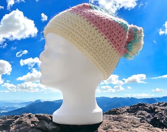 Winter Chic: Colorful crochet pompom hat in aquamarine, beige and pink, a unique and stylish winter fashion accessory.