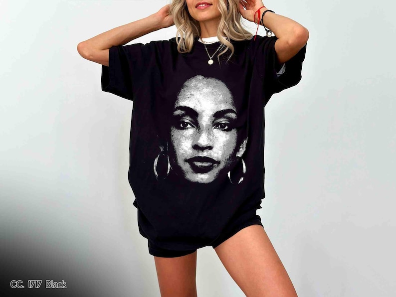 Peut inclure: T-shirt noir avec un imprim&eacute; graphique d'un visage de femme. Le visage est en noir et blanc et porte de grandes boucles d'oreilles.