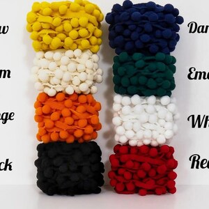 May include: A collection of colorful pom-pom trim in various shades, including yellow, cream, orange, black, dark blue, emerald, white, and red. The image displays the colors with corresponding text labels.