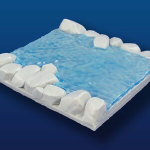 Op de afbeelding: Een witte plastic miniatuur terreintegel met een blauwe waterpartij en witte stenen randen.