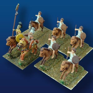 May include: Miniature figurines of mounted warriors, each with a shield and spear, are arranged on rectangular bases. The horses are brown, and the warriors wear white tunics. The bases are covered in green, simulating grass.