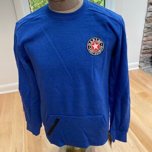 May include: A royal blue sweatshirt with a Harley-Davidson logo patch on the chest. The patch features a red star and the brand name in a circular design. The sweatshirt has a front pocket with a black zipper detail.