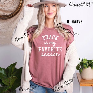 May include: A mauve t-shirt with the text "TRACK is my FAVORITE season" in white lettering.