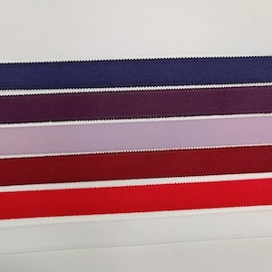 May include: A collection of six parallel strips of elastic ribbon arranged horizontally. The colors include dark navy blue, deep plum, light lavender, dark burgundy, bright red, and white. Each strip features a textured, scalloped edge finish.