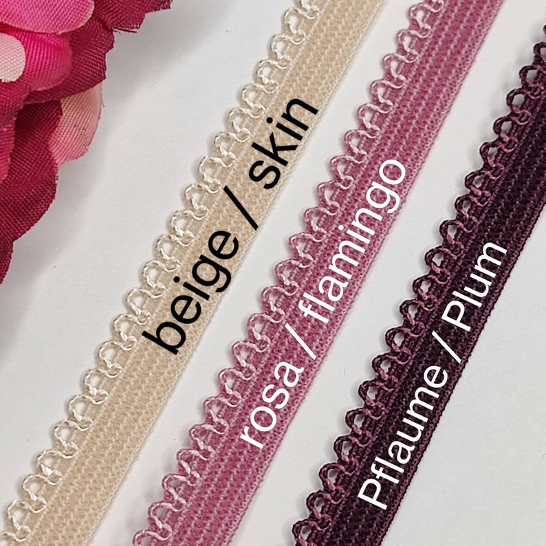 May include: Three different colors of elastic trim with scalloped edges. The colors are beige/skin, rosa/flamingo, and pflaume/plum.