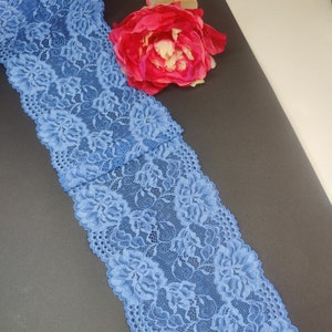 May include: A close-up of blue lace trim with a floral pattern. The lace is delicate and intricate, with a soft, flowing texture.