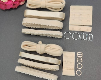 May include: A set of beige bra strap making supplies including elastic, ribbon, and hook and eye closures.