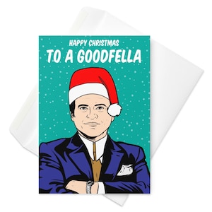 Puede incluir: Tarjeta de Navidad con una ilustración de un hombre con gorro de Papá Noel, traje azul y corbata dorada. La tarjeta tiene el texto "HAPPY CHRISTMAS TO A GOODFELLA" sobre un fondo turquesa con puntos blancos. En un sobre blanco.