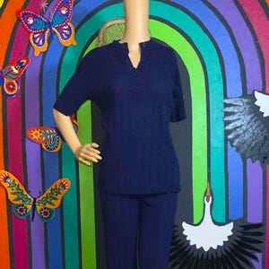 May include: A navy blue knit pantsuit with a short-sleeved top and long pants. The top has a button-up collar and the pants have a straight leg.
