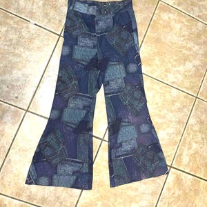 May include: Blue flared pants with a repeating pattern of denim-like rectangles and squares. The pants have a high waist and a button and zipper closure. The fabric has a faded, vintage look.
