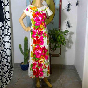 May include: White dress with a vibrant floral pattern in shades of pink, red, yellow, and green. The dress features a scoop neckline and short sleeves. The dress is displayed on a mannequin.