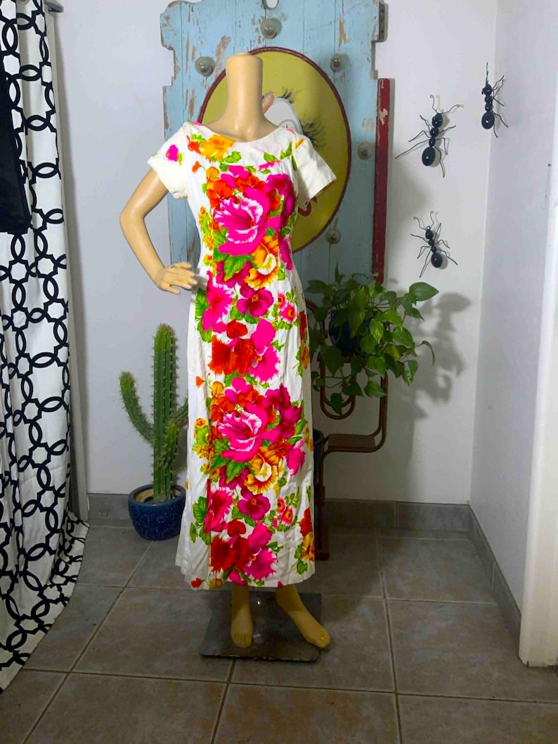 May include: White dress with a vibrant floral pattern in shades of pink, red, yellow, and green. The dress features a scoop neckline and short sleeves. The dress is displayed on a mannequin.