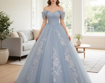 Könnte beinhalten: Ein hellblaues schulterfreies Kleid mit weitem Rock und weißer Blumenstickerei. Das Kleid hat einen Sweetheart-Ausschnitt und kurze, gepuffte Ärmel. Das Kleid ist bodenlang und scheint aus Tüll zu sein.