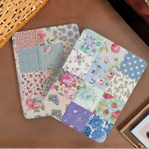 May include: Two floral patchwork tablet covers. One cover features a mix of pink, red, and blue floral patterns. The other cover has a variety of floral and polka dot designs in pink, blue, and purple.