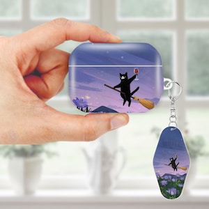 May include: A blue case for wireless earbuds and a matching keychain. Both feature a whimsical illustration of a black cat riding a broom and holding a glass of wine against a purple and blue night sky background.
