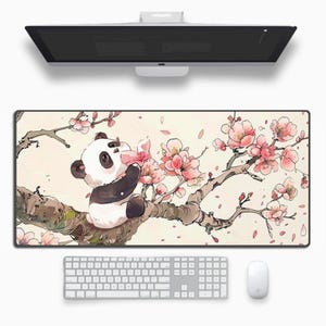 May include: A rectangular desk mat with a panda bear illustration. The panda is on a branch with pink cherry blossoms. A white keyboard and mouse are below the mat, with a computer monitor above.