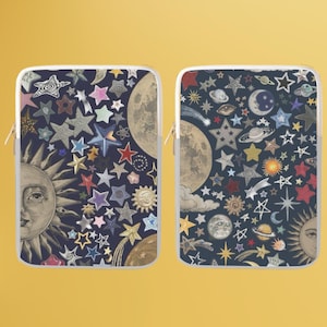 May include: Two laptop sleeves with a celestial design featuring a sun, moon, and stars on a dark blue background. The sleeves are white with a zipper.