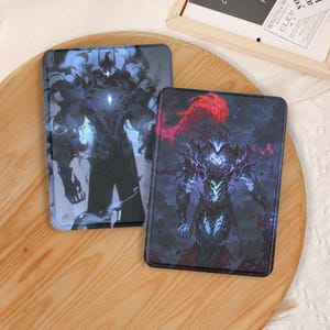 Könnte beinhalten: Zwei rechteckige Hüllen mit Fantasy-Kunst. Eine Hülle zeigt eine dunkle Figur mit blauen Akzenten, die andere eine ähnliche Figur mit roten und violetten Akzenten. Die Hüllen liegen auf einem Holztablett.