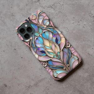 Op de afbeelding: Een telefoonhoesje met een glas-in-loodontwerp in roze, blauw en goud. Het ontwerp is ingewikkeld en heeft een bloemenpatroon.