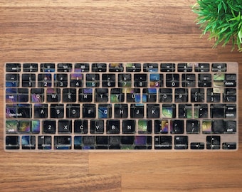 May include: A black keyboard with iridescent keys. The keys have a variety of colors, including blue, green, purple, and pink. The keyboard has a standard layout with function keys, number keys, and letter keys. The keyboard is on a wooden surface.