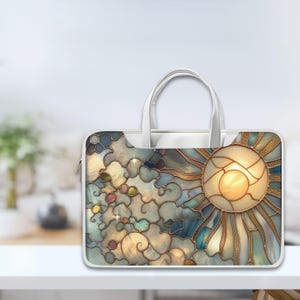 Könnte beinhalten: Weiße Laptoptasche mit einem Buntglasdesign mit Sonne, Wolken und Sternen in Blau-, Gold- und Cremetönen. Die Tasche hat einen Griff und einen Reißverschluss.