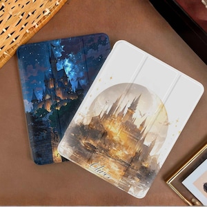 May include: Two tablet cases with castle illustrations. One case shows a dark blue night sky with a castle, the other has a white background with a castle design and the name "Oliver".